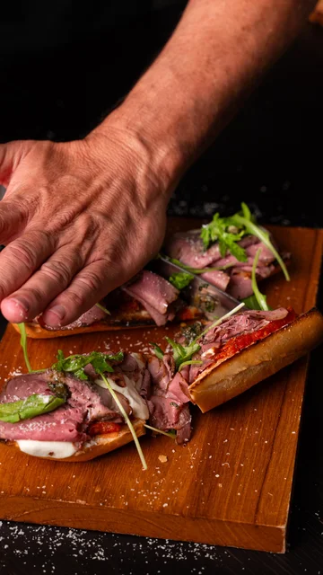 Chef pressing a steak sandwich on a cutting board
