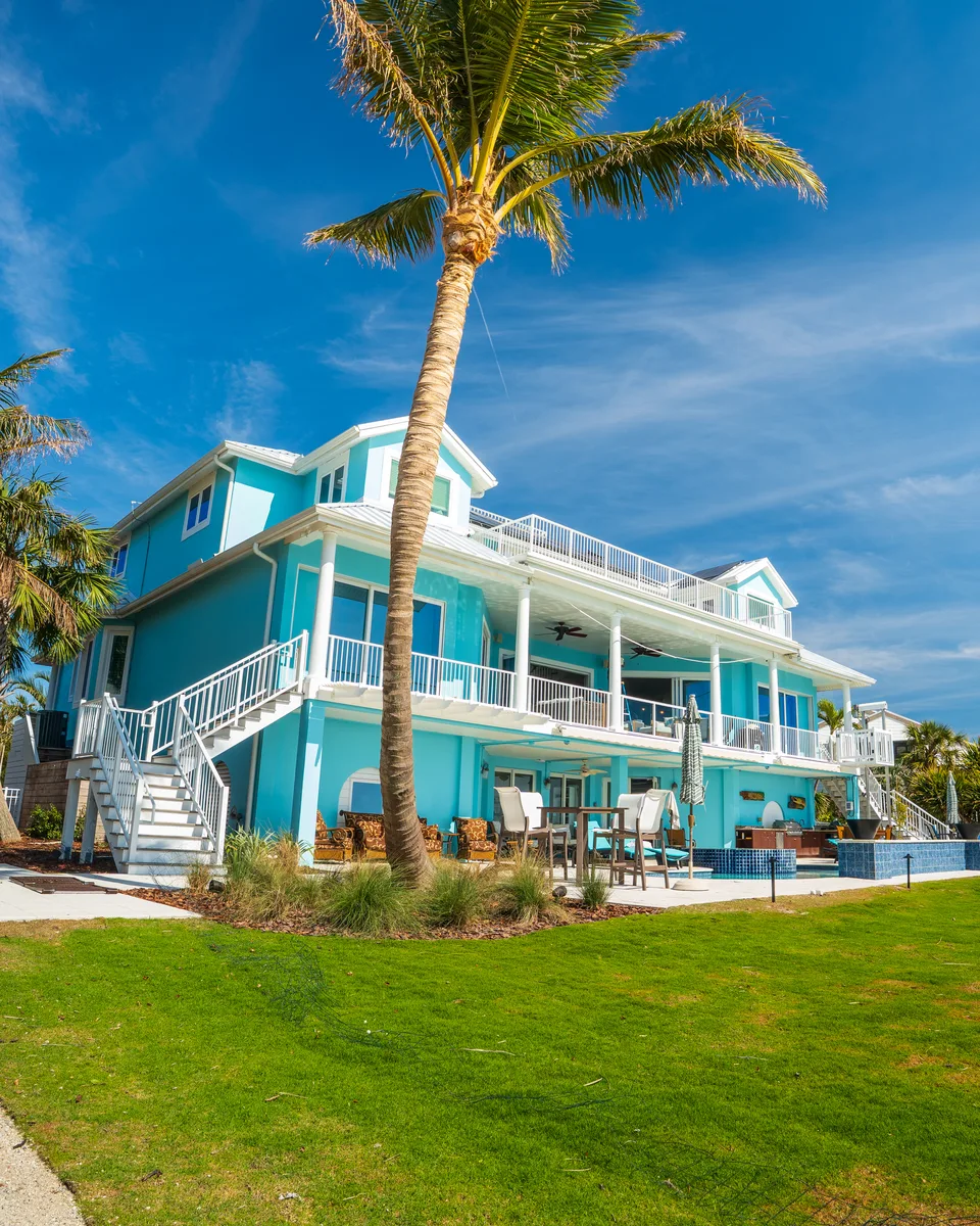 Freshly painted turquoise beach house under a palm tree