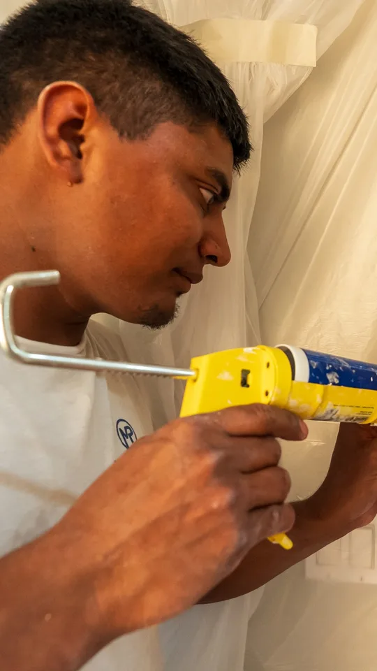 Painter caulking a door frame
