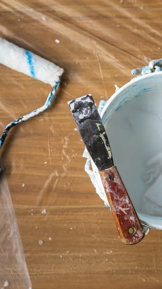 Roller, scraper and paint bucket laid out on the drop cloth